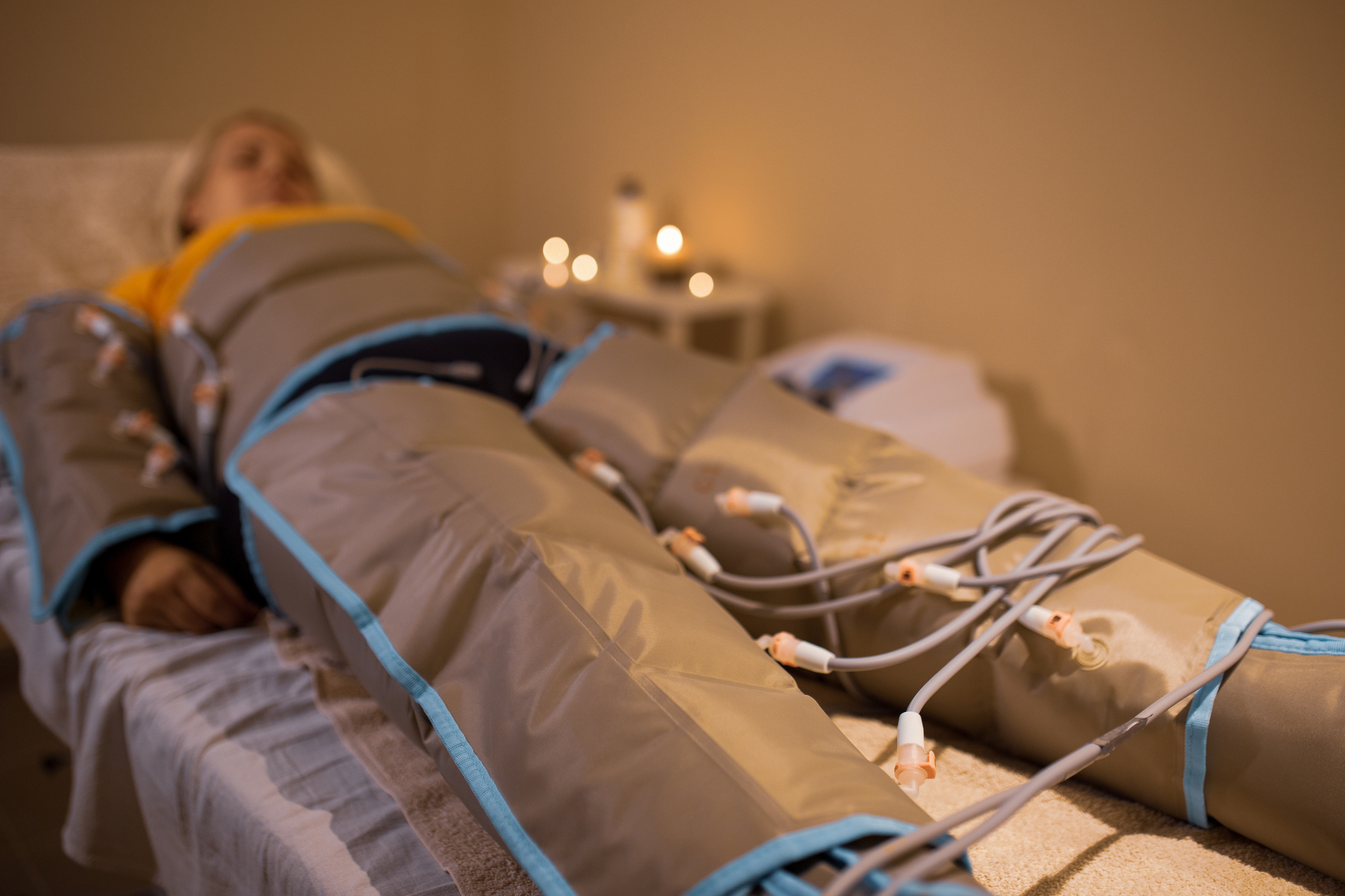Woman in Beauty Clinic Having Pressure Therapy Lying Down in Pressotherapy Suit
